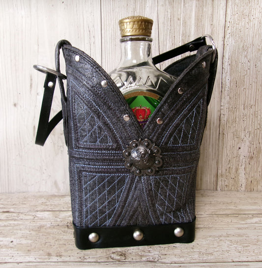 Bottle of whiskey  in a decorative black and gray holder on a wooden surface