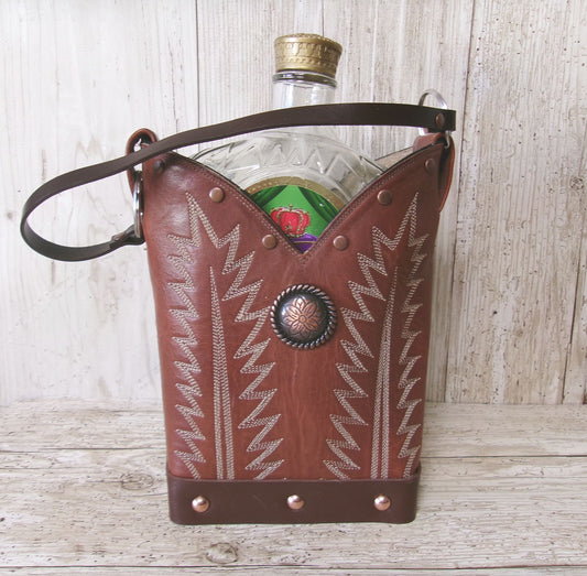 Brown leather flask with decorative patterns and a bottle inside on a wooden surface.