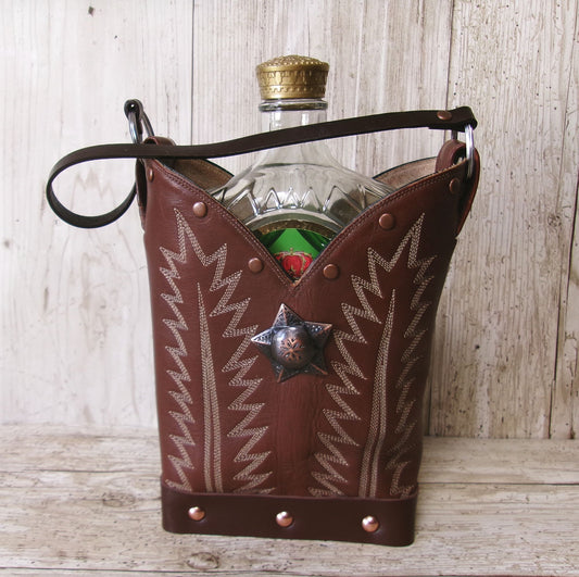 Brown leather cowboy-style bottle holder with a star design on a wooden surface.