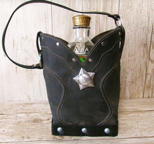 Black leather flask holder with star accent containing a bottle on a wooden surface