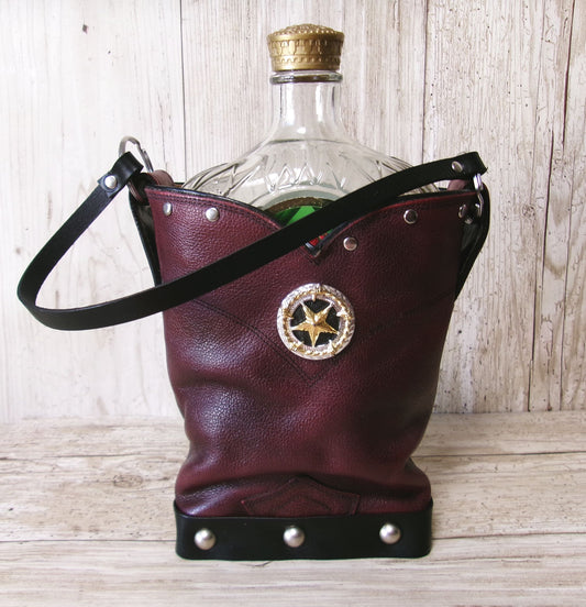 Burgundy leather bag with star emblem holding a glass bottle on a wooden surface