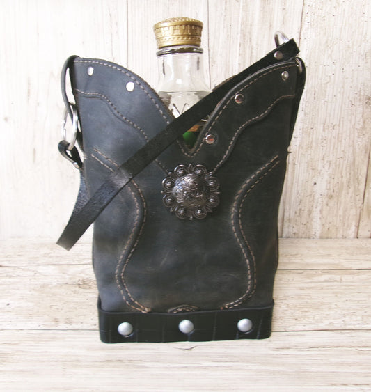 Black leather flask with decorative emblem on a wooden surface