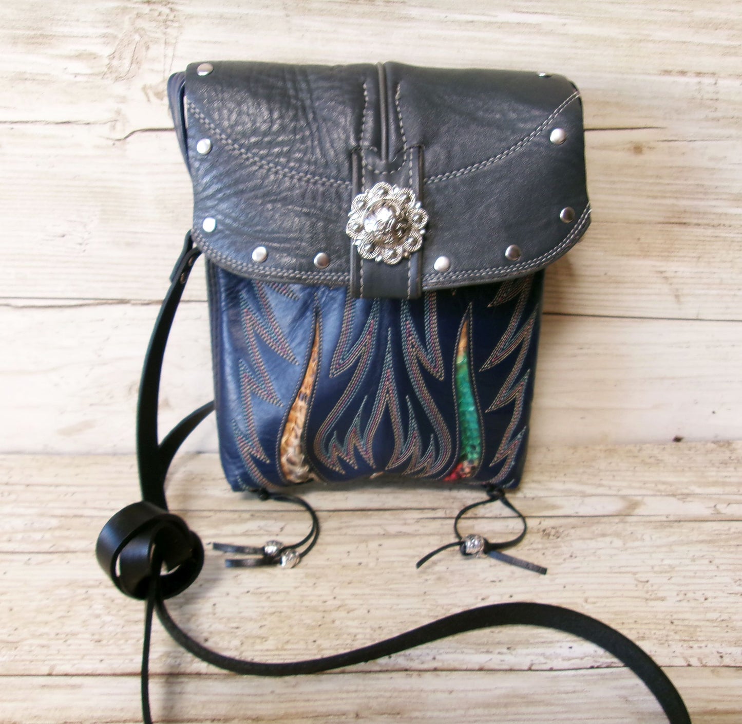 Blue leather bag with floral design and decorative elements on a wooden surface