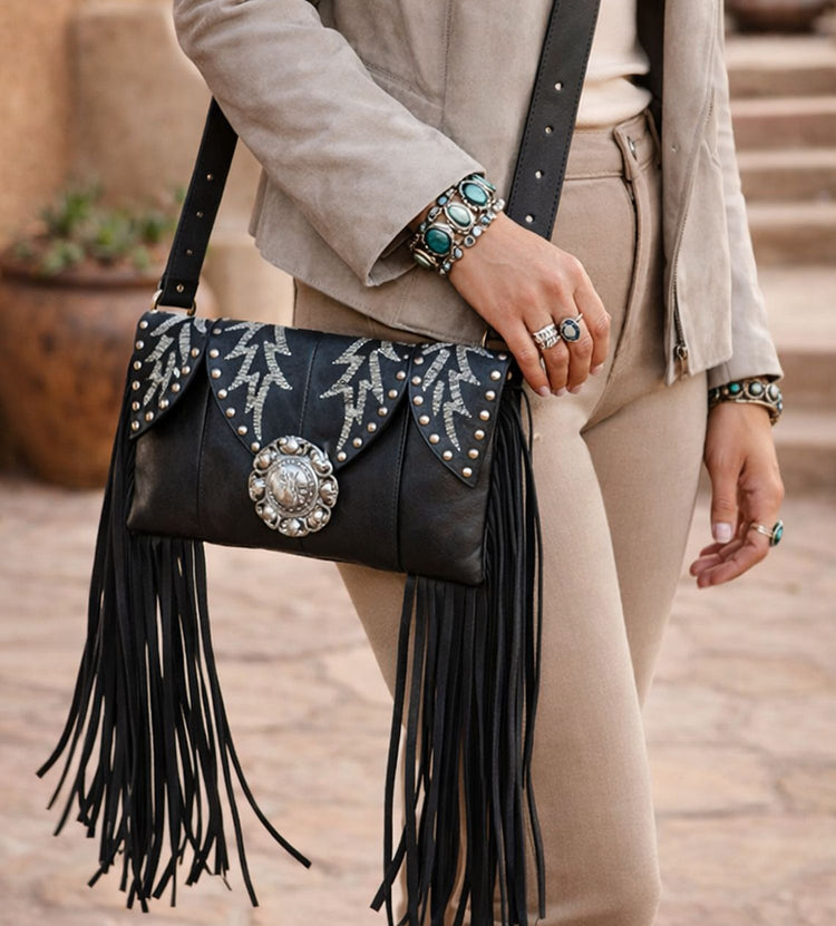 woman carrying black leather cowboot purse with long fringe