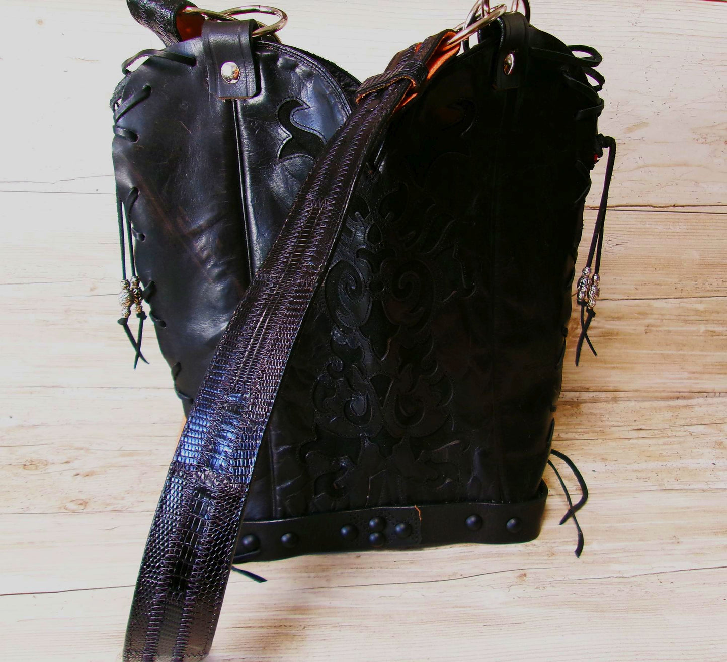 Black leather handbag with textured strap on a wooden surface