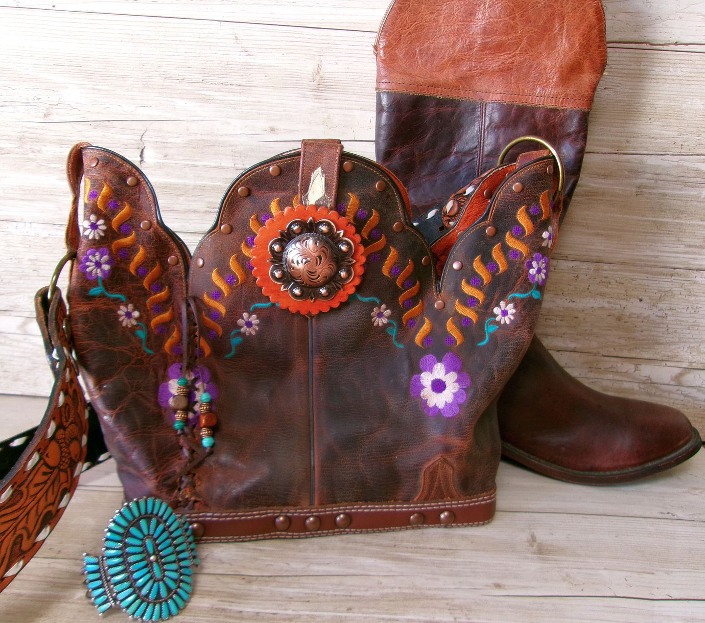 Decorative brown boots with floral patterns and beads on a wooden surface
