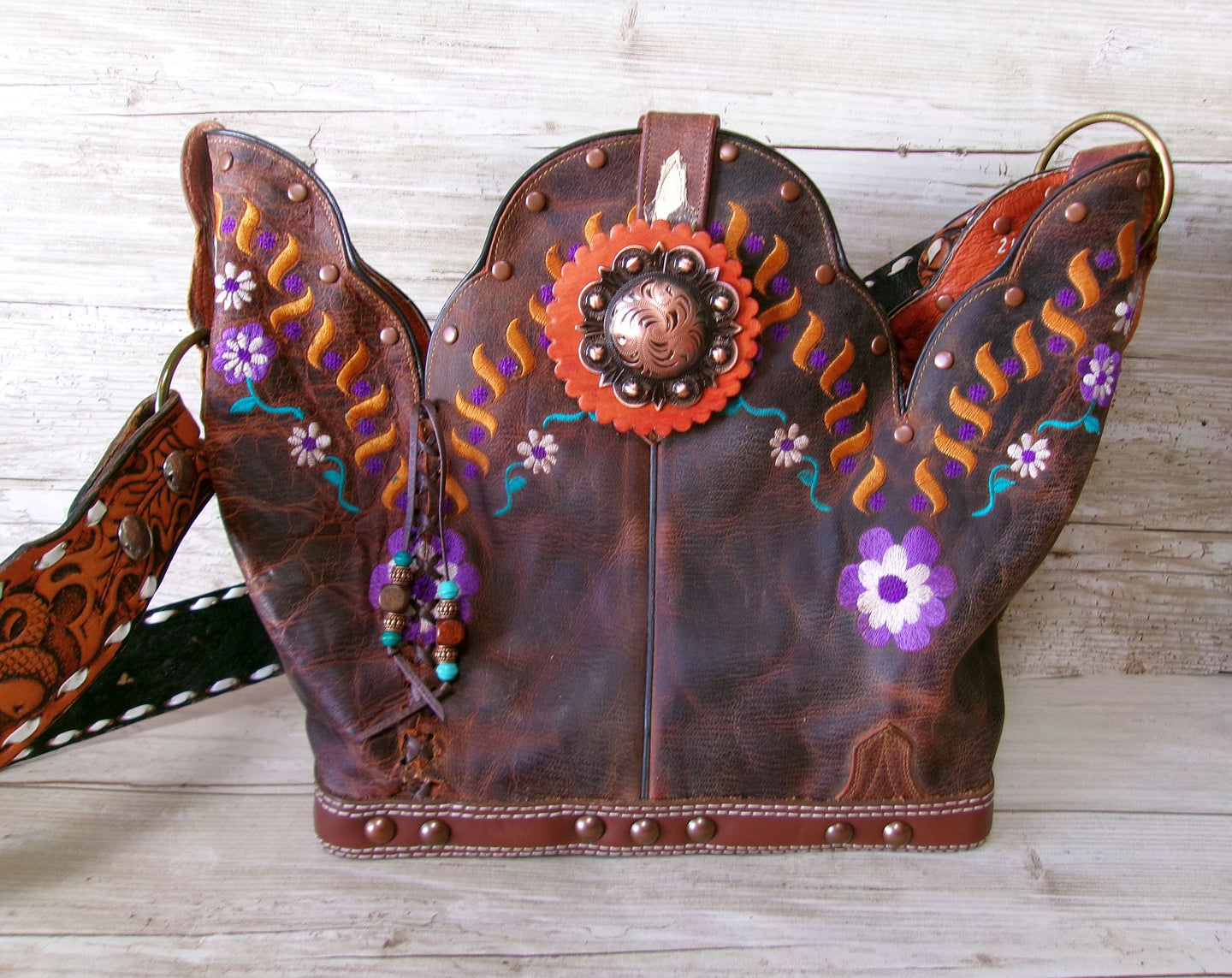 Decorative leather bag with floral patterns and beads on a wooden surface