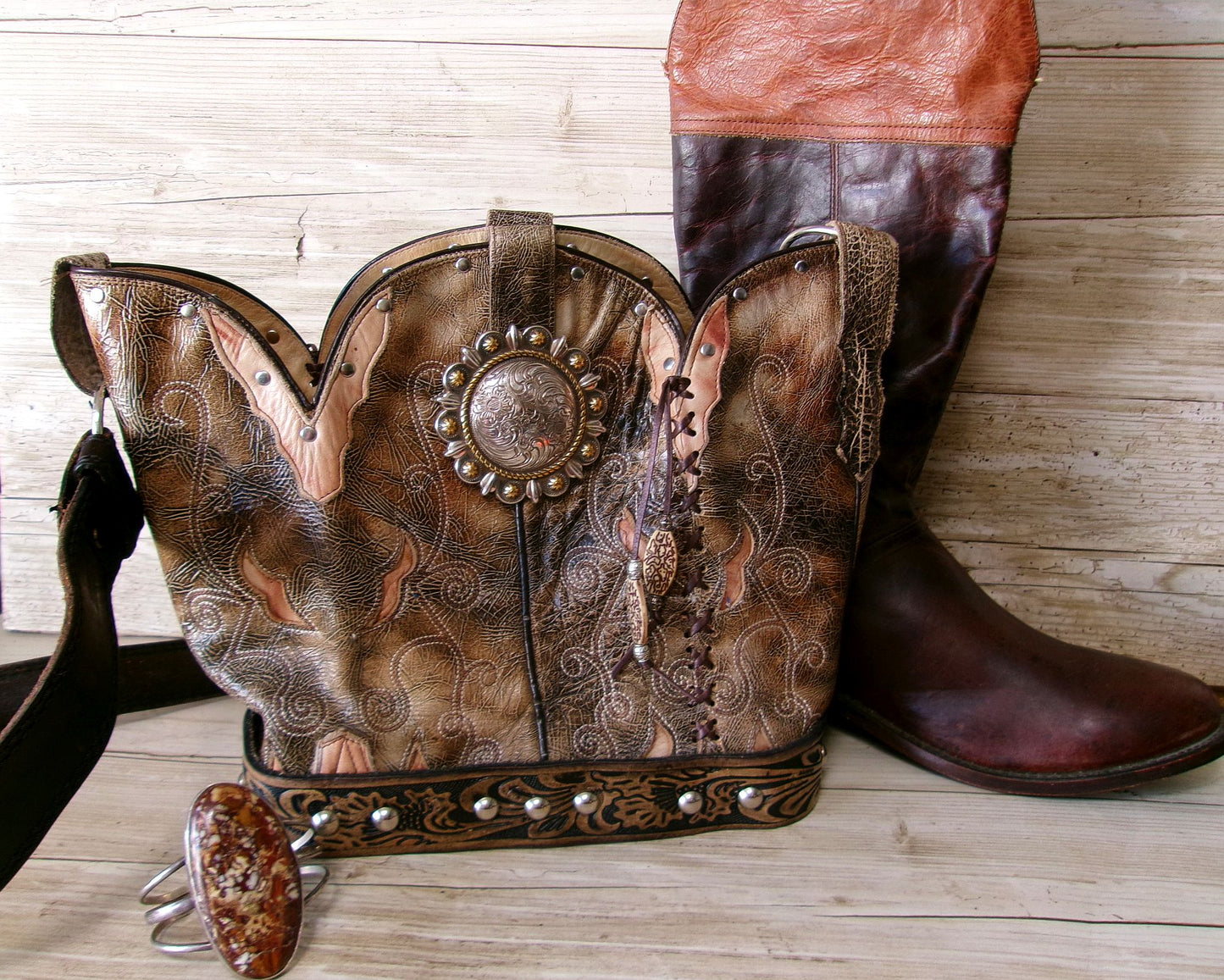 Pair of intricately designed cowboy boots with detailed patterns on a wooden surface.