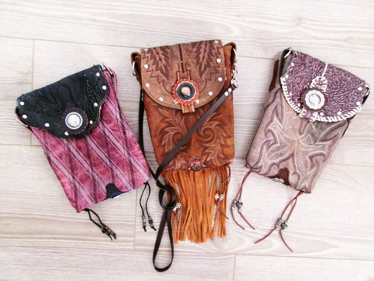 Three decorative handbags with intricate designs on a light wooden surface