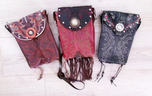 Three decorative bags with intricate patterns and fringes on a light wooden surface.