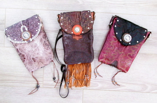 Three decorative bags with fringe on a light wooden surface