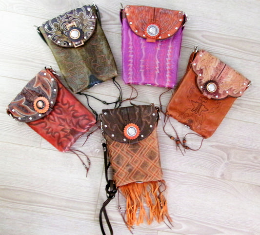 Five colorful leather pouches with intricate designs on a light wooden surface