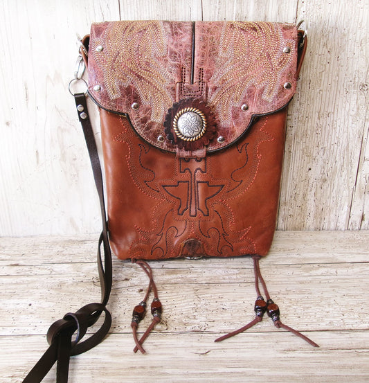 Brown leather bag with intricate designs on a wooden surface