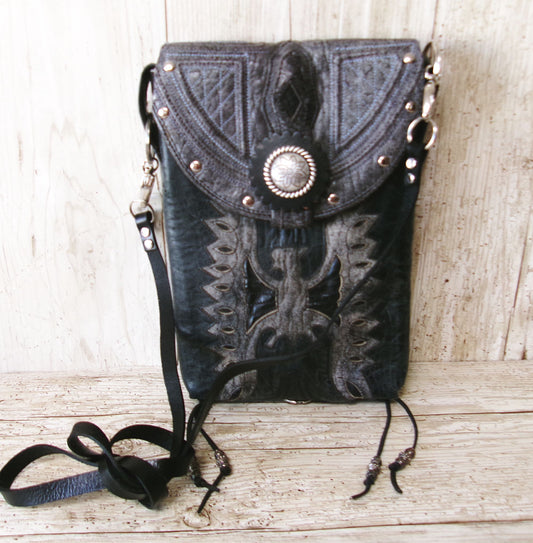 Black leather pouch with decorative patterns and a central button on a wooden surface