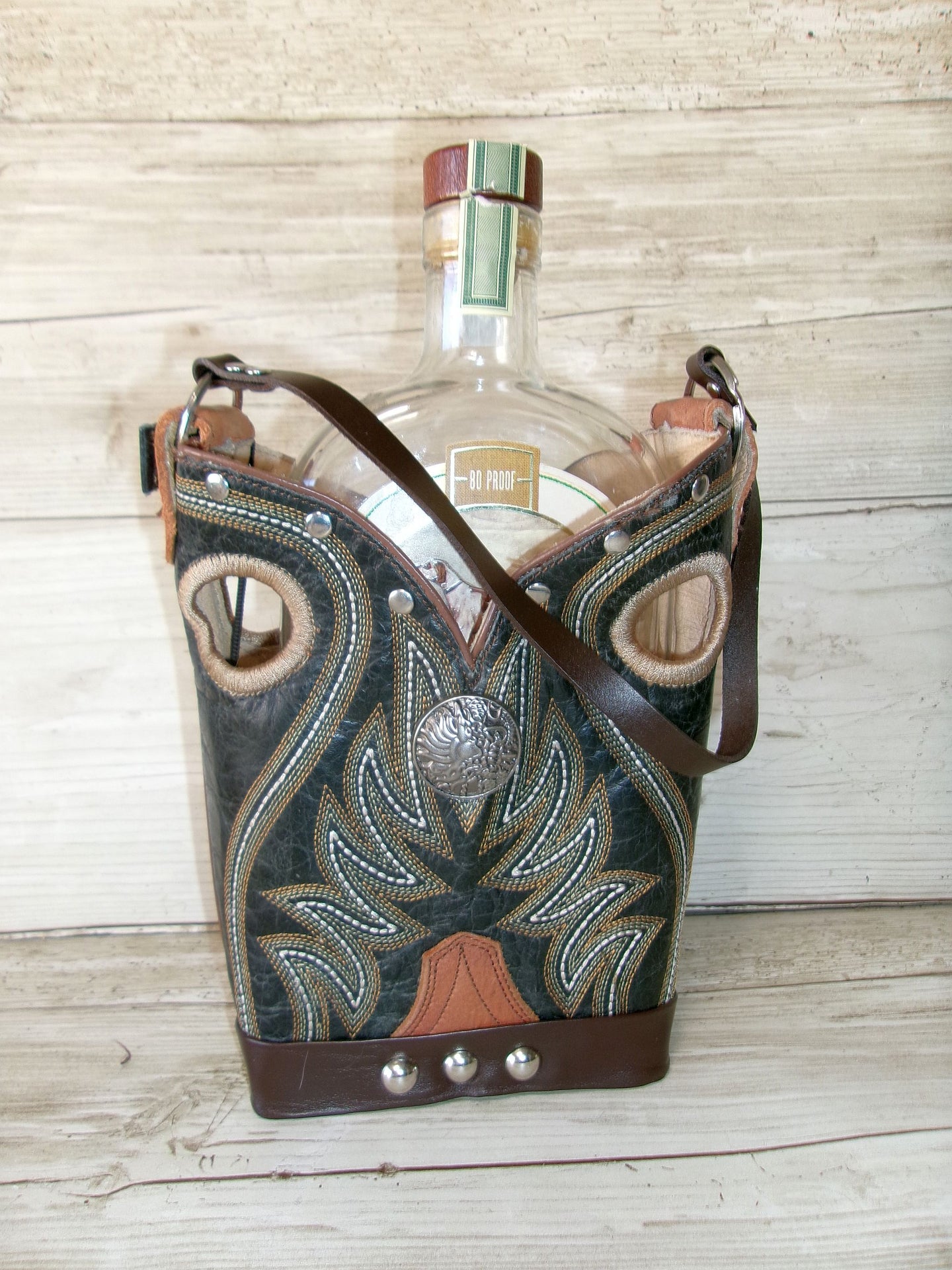 Decorative leather bottle holder with a bottle inside on a wooden surface