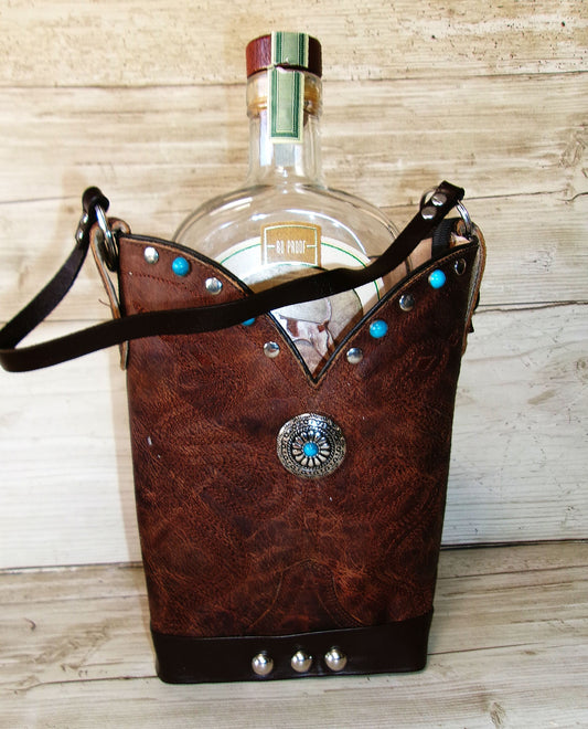 Brown leather bag with decorative studs holding a bottle against a wooden background