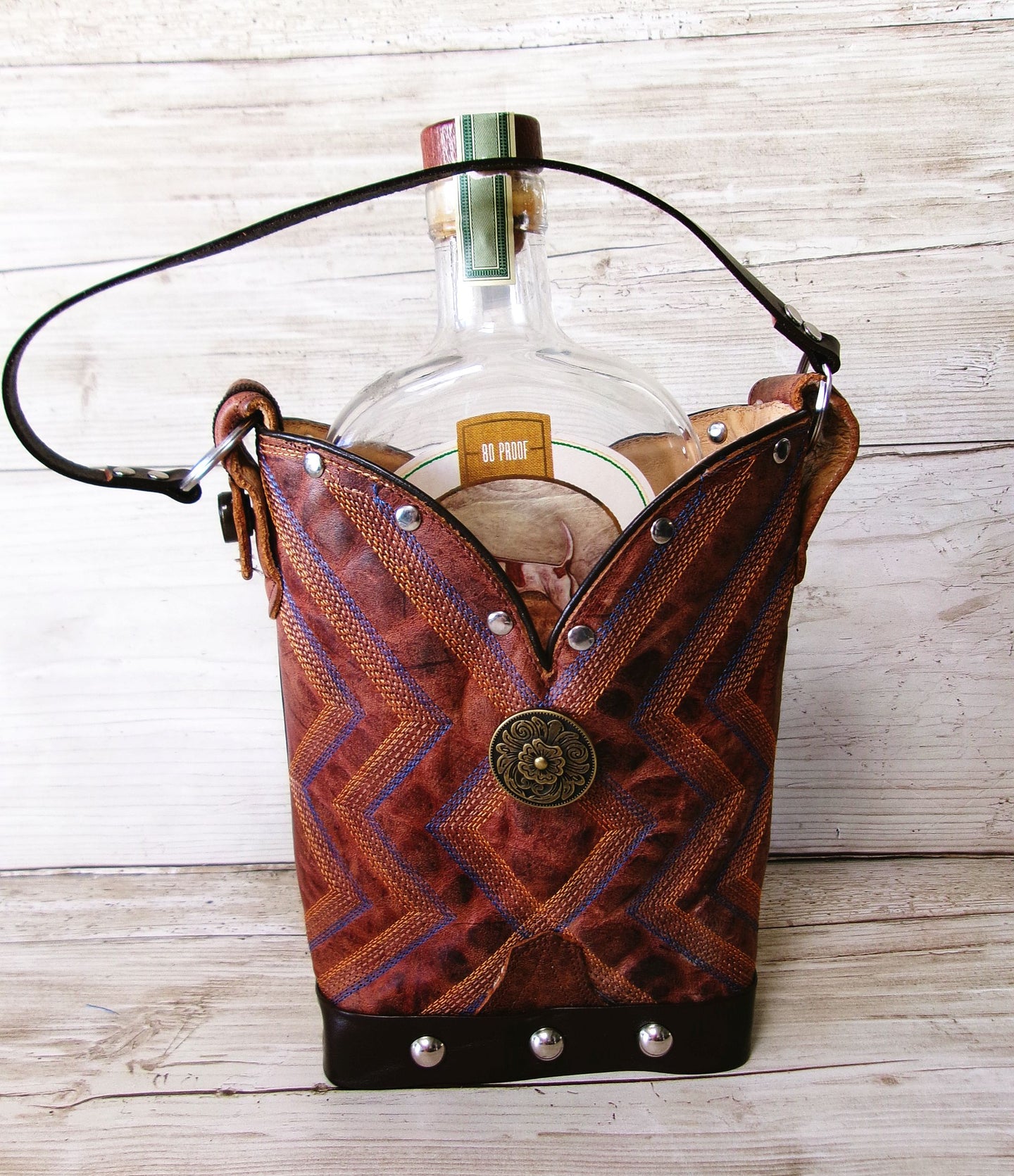 Brown leather bottle holder with decorative patterns on a wooden surface