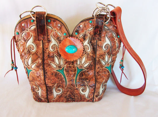 Cowboy boot-shaped handbag with intricate designs and turquoise stones on a white background