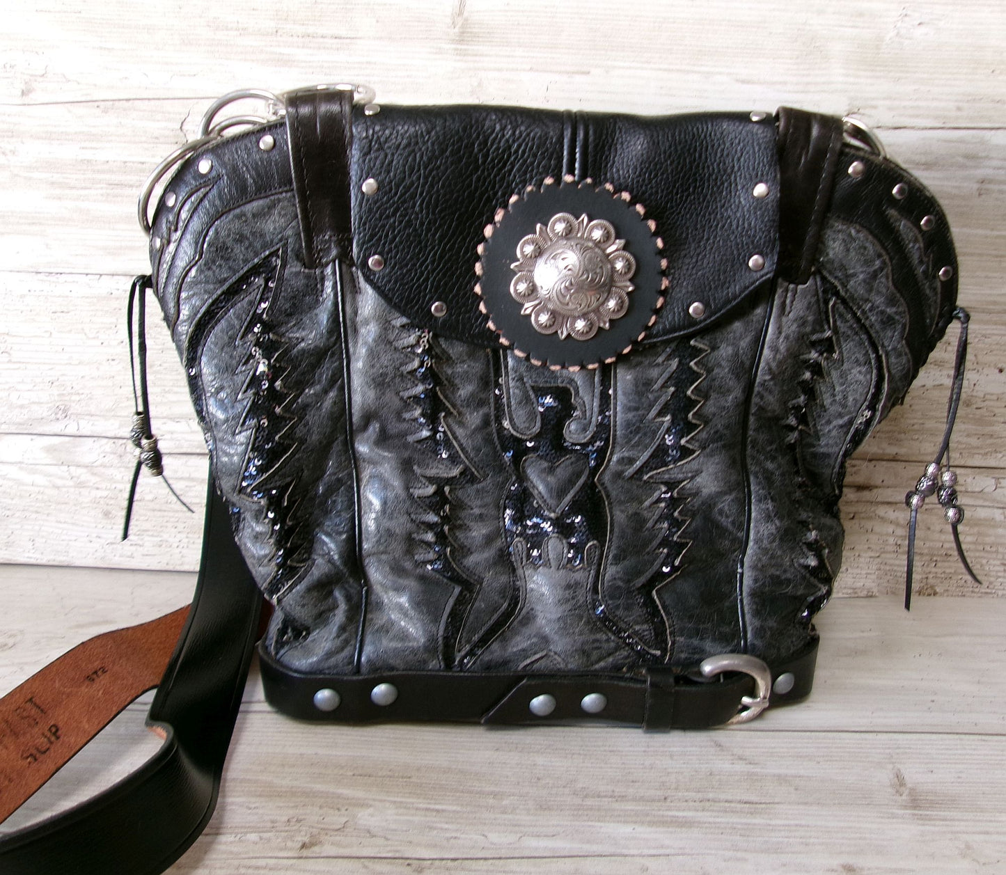 Black leather handbag with decorative elements on a wooden surface