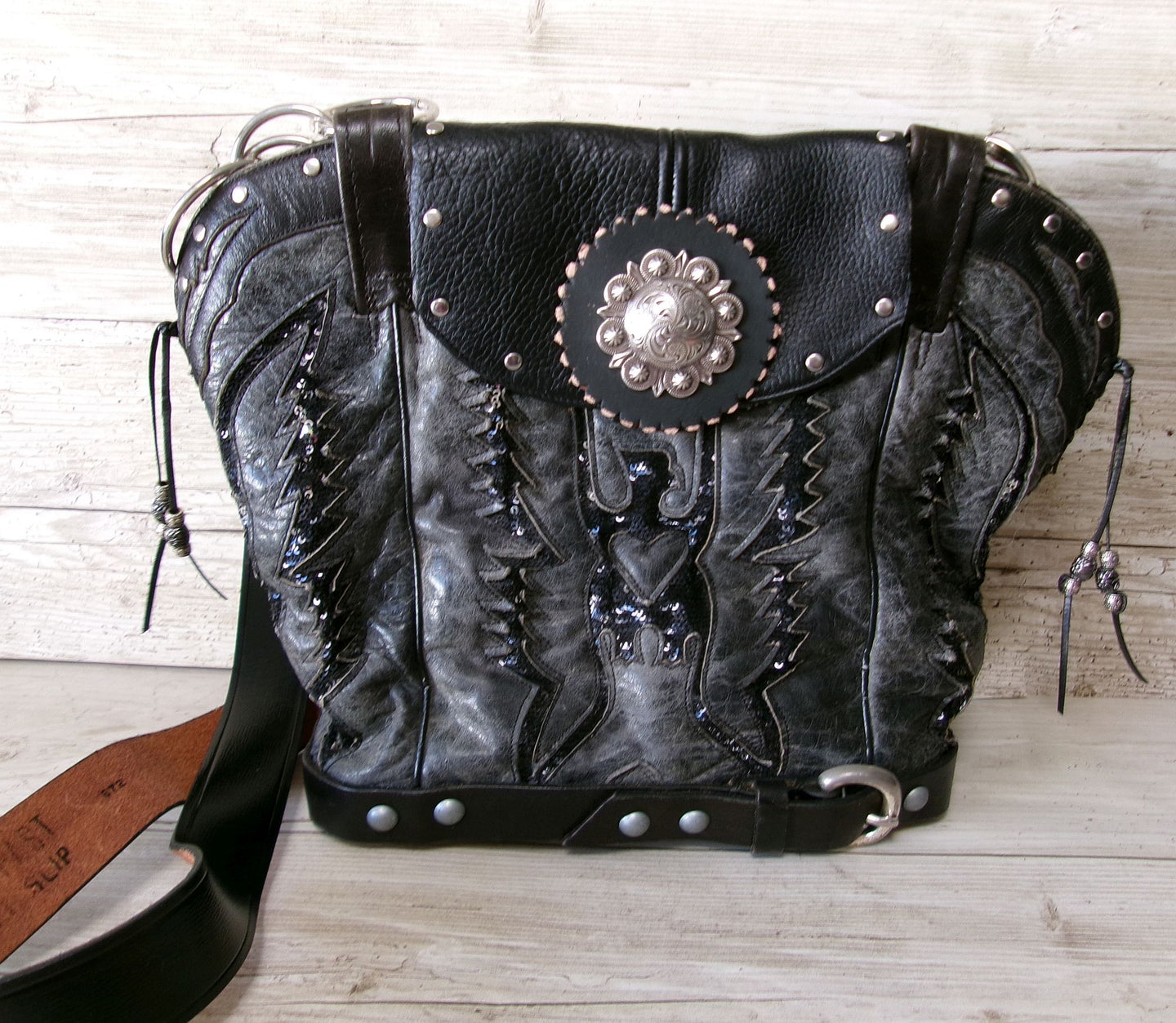 Black leather handbag with decorative elements on a wooden surface