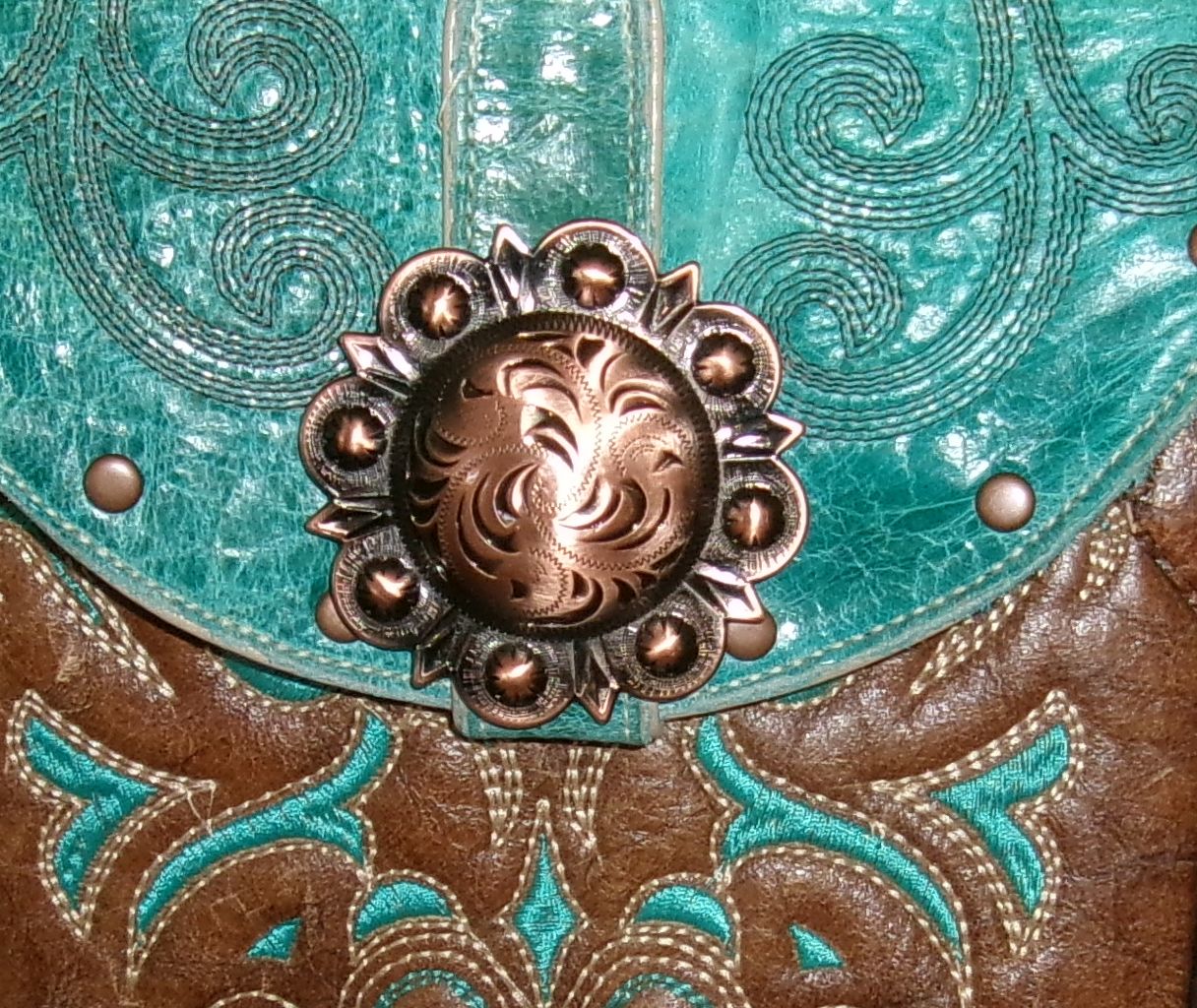 Close-up of a turquoise and brown leather bag with decorative metal clasp