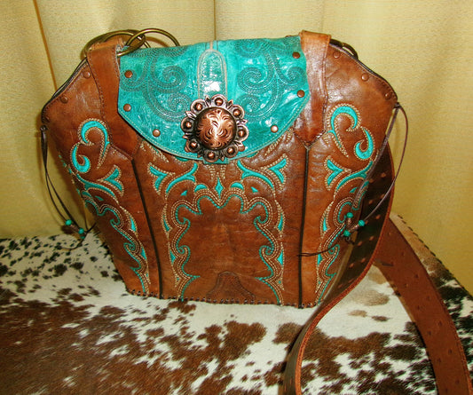 Brown leather handbag with turquoise accents and decorative studs on a cowhide surface.