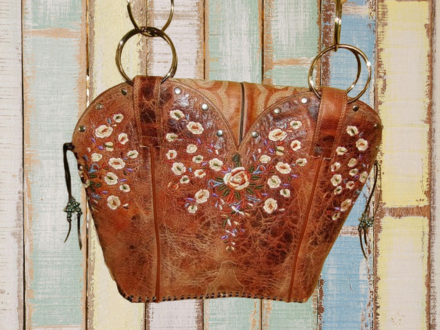 Brown leather bag with floral embroidery on a wooden background