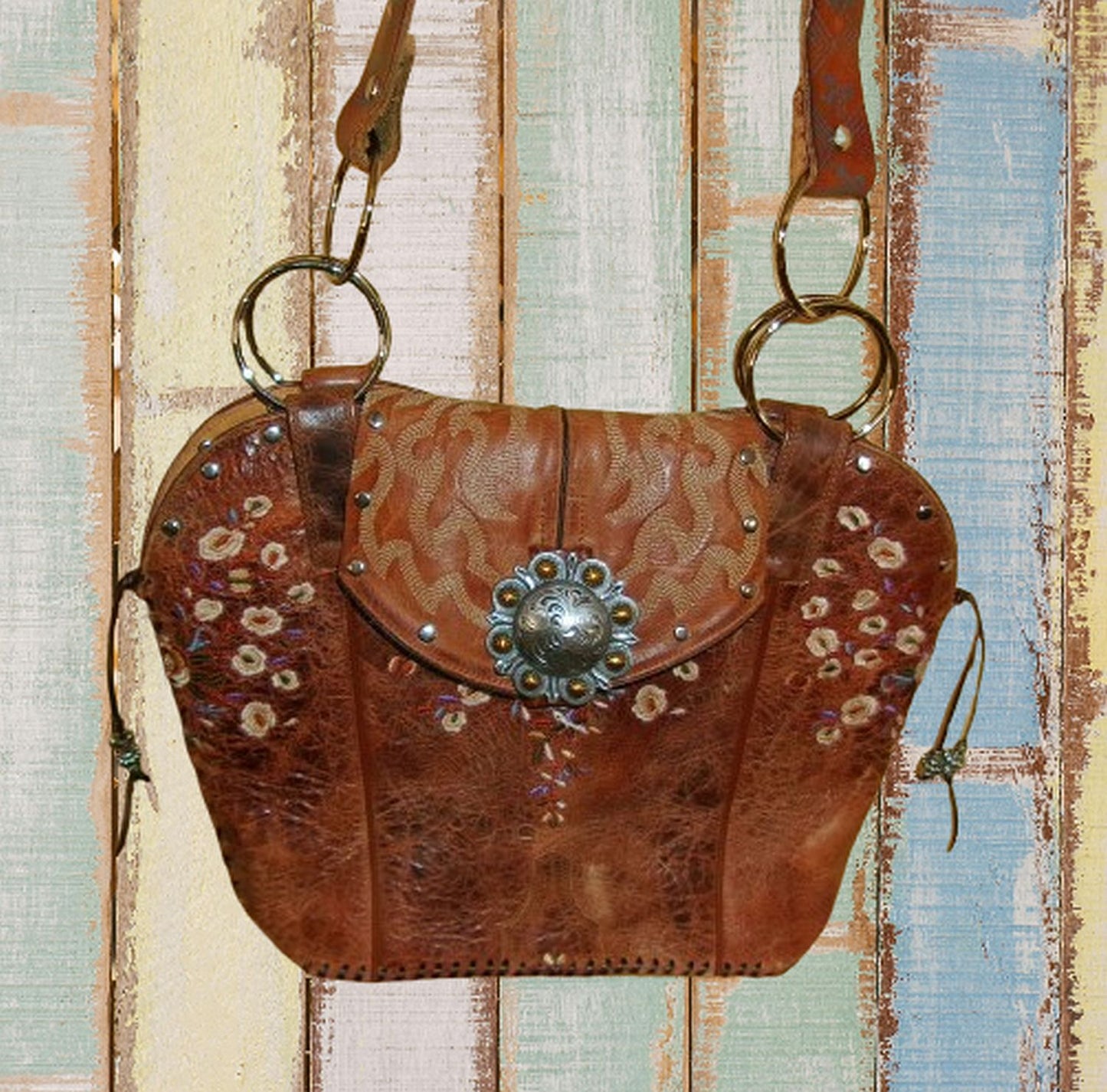 Brown leather handbag with decorative elements on a textured background