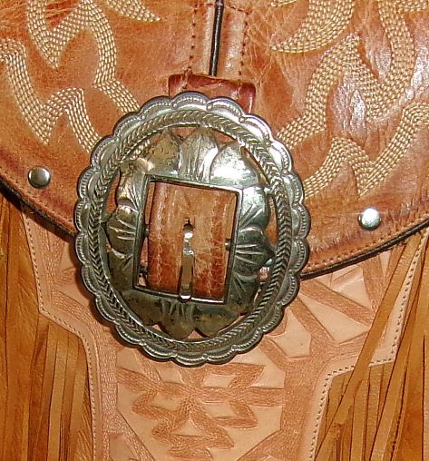 Close-up of a silver belt buckle on a brown leather background