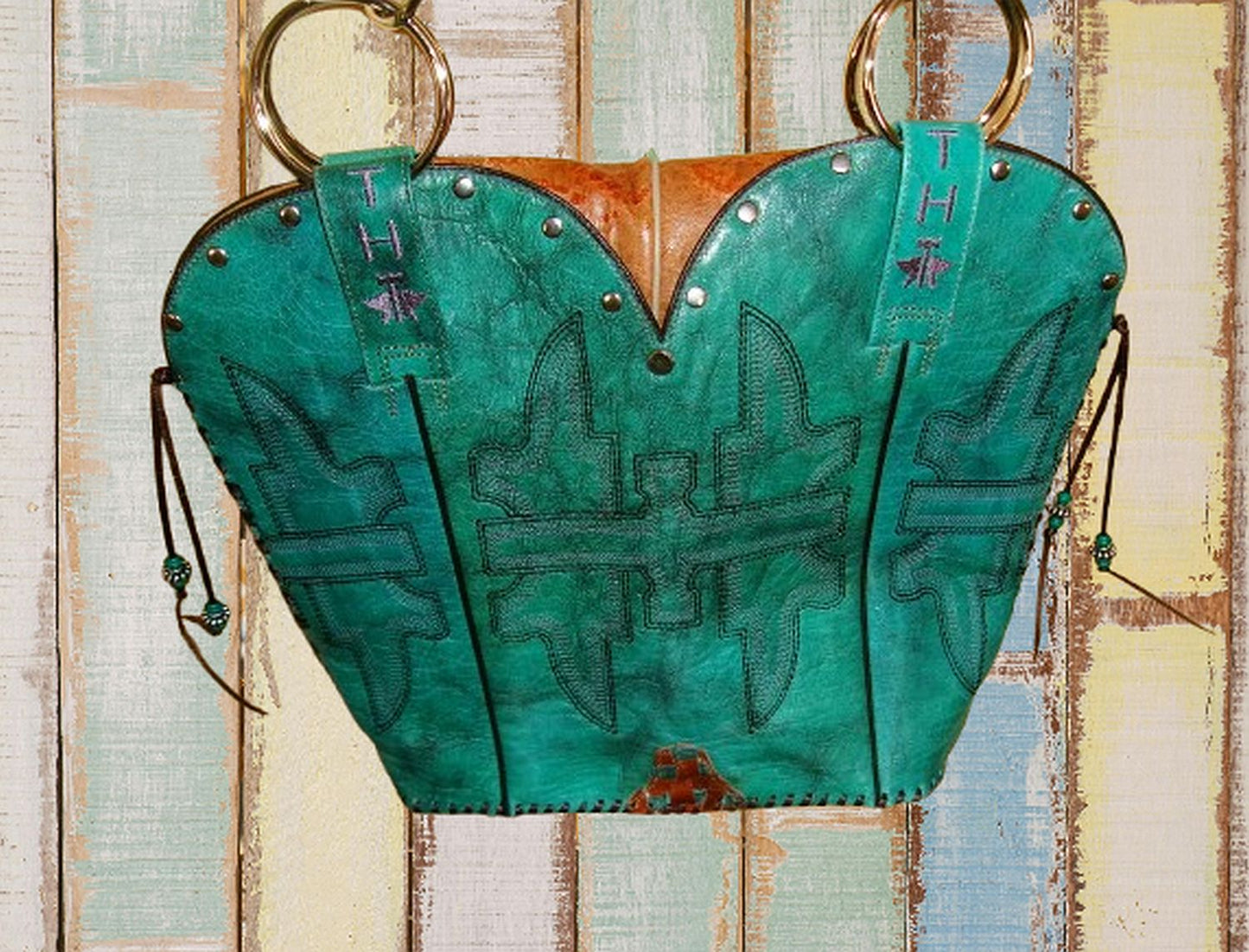 Green leather saddle pad with intricate patterns on a wooden background