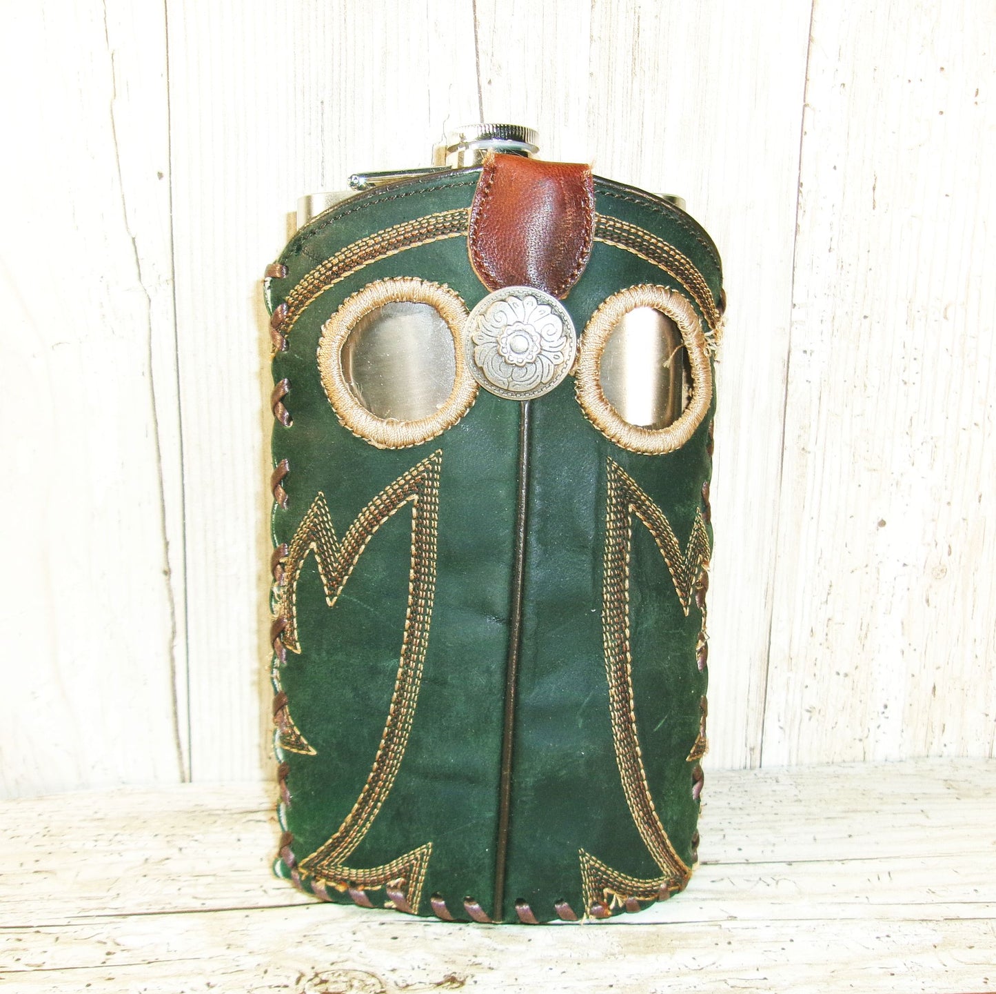 Green leather bag with decorative elements on a wooden surface