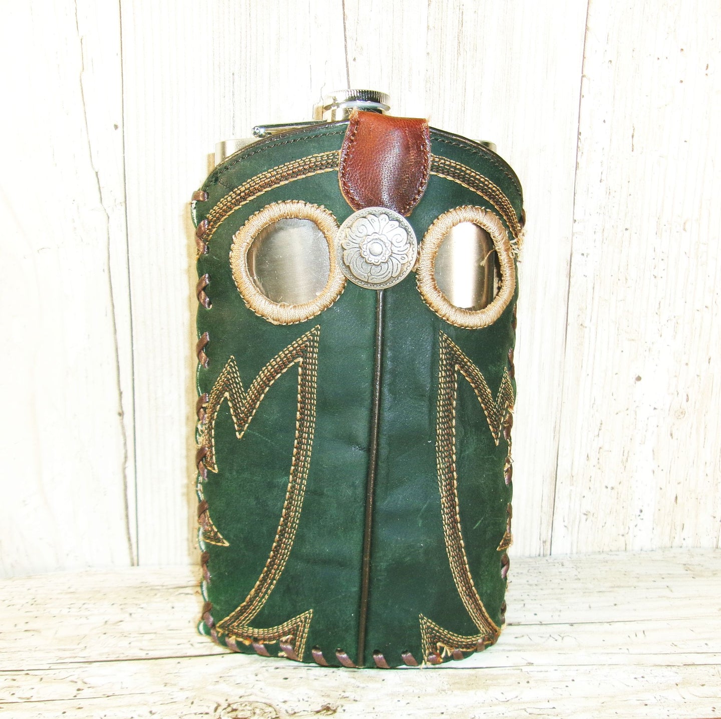 Green leather bag with decorative elements on a wooden surface