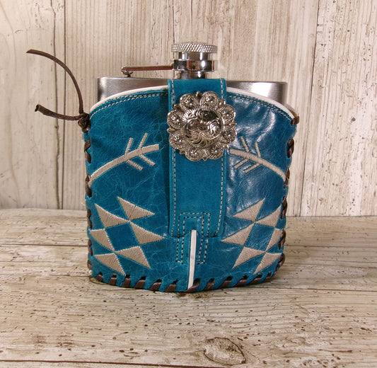 Flask with blue leather wrap and decorative clasp on a wooden surface