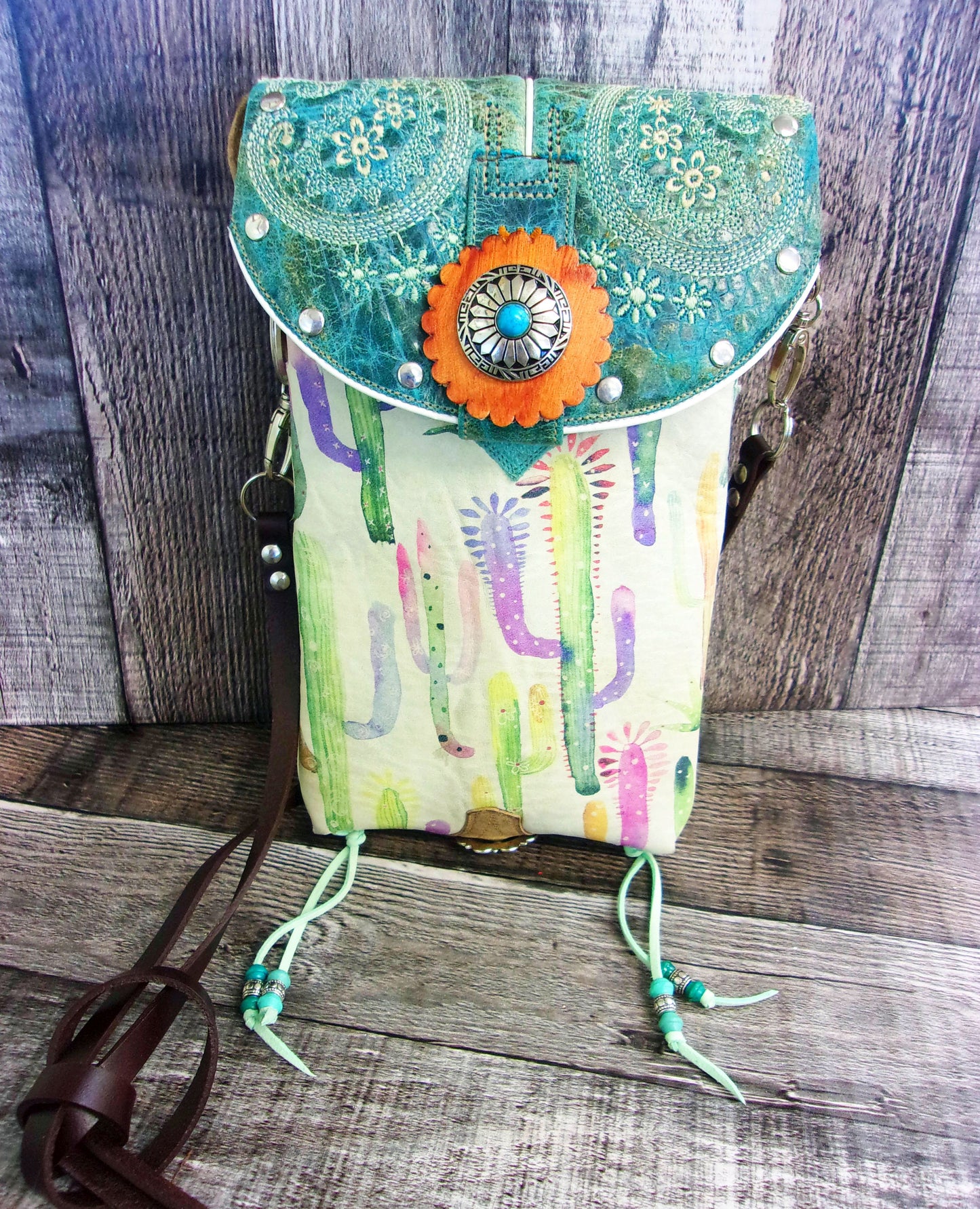 Colorful handbag with floral design and orange flower on a wooden surface