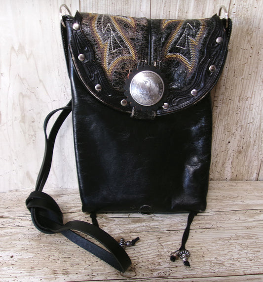 Black leather bag with decorative metal clasp on a wooden surface
