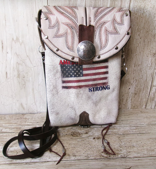 Leather crossbody bag with American flag and 'America Strong' text on a wooden surface