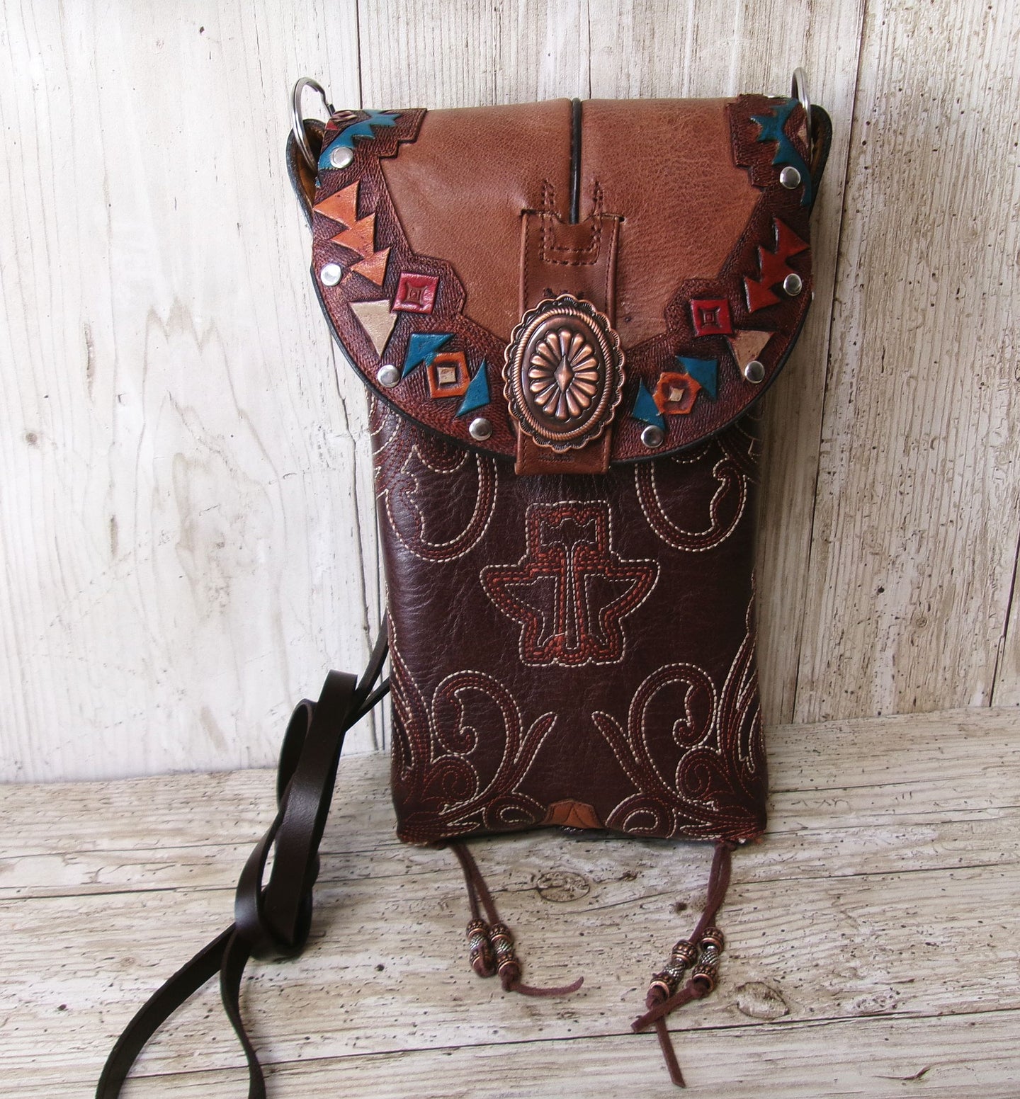 Brown leather bag with decorative patterns and studs on a wooden surface
