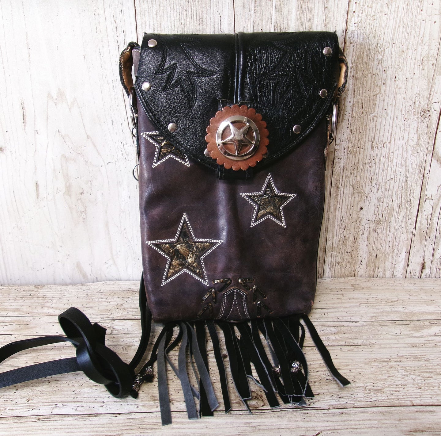 Leather bag with star designs and fringes on a wooden surface