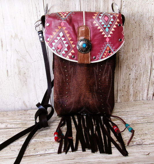 Brown leather backpack with red geometric patterned flap and fringes on a wooden surface