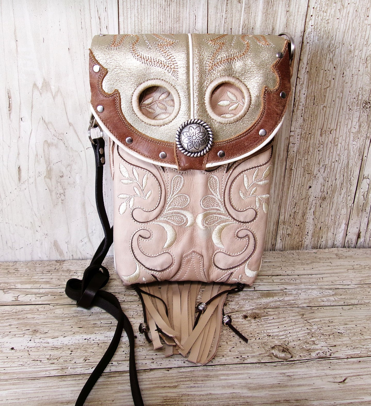 Decorative leather pouch with owl design on a wooden surface