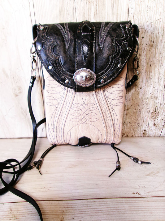 Black and white leather handbag with decorative elements on a wooden surface