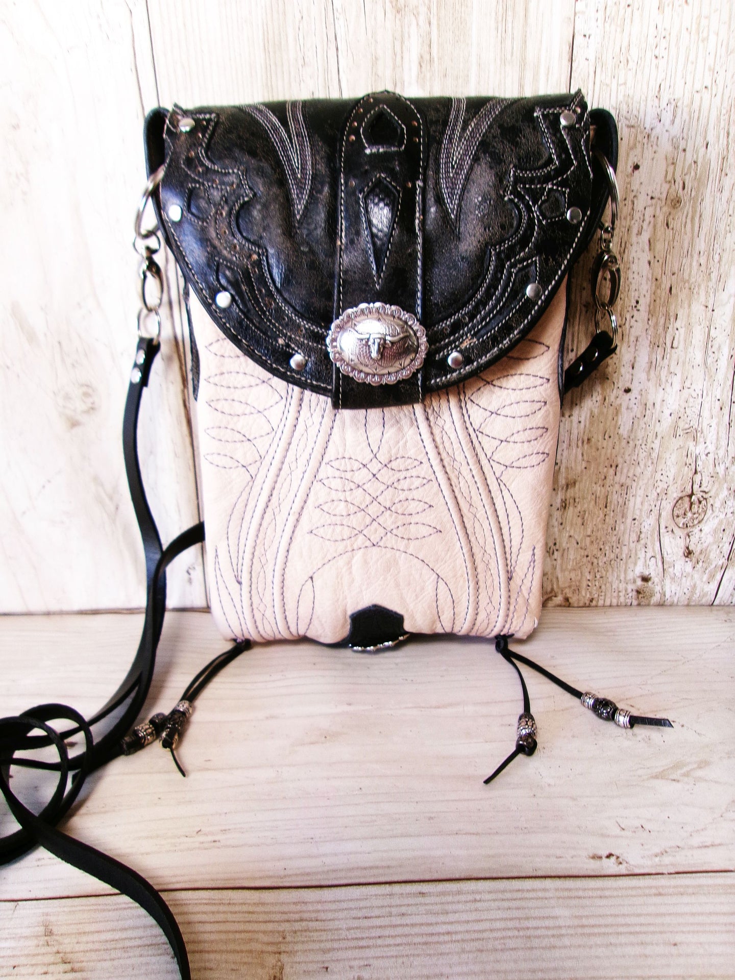 Black and white leather handbag with decorative elements on a wooden surface