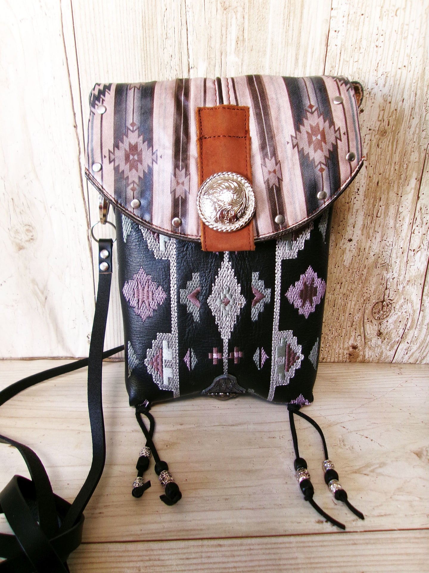 Patterned handbag with decorative strap and concho on a wooden surface