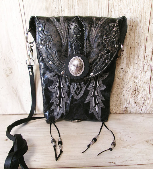 Black leather handbag with intricate silver embroidery on a wooden surface