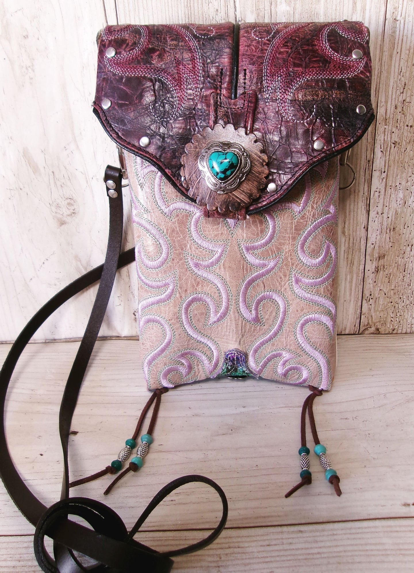Handbag with intricate design and turquoise heart emblem on a wooden surface