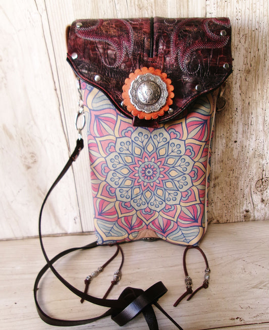 Multicolored patterned bag with leather flap and decorative element on a wooden surface