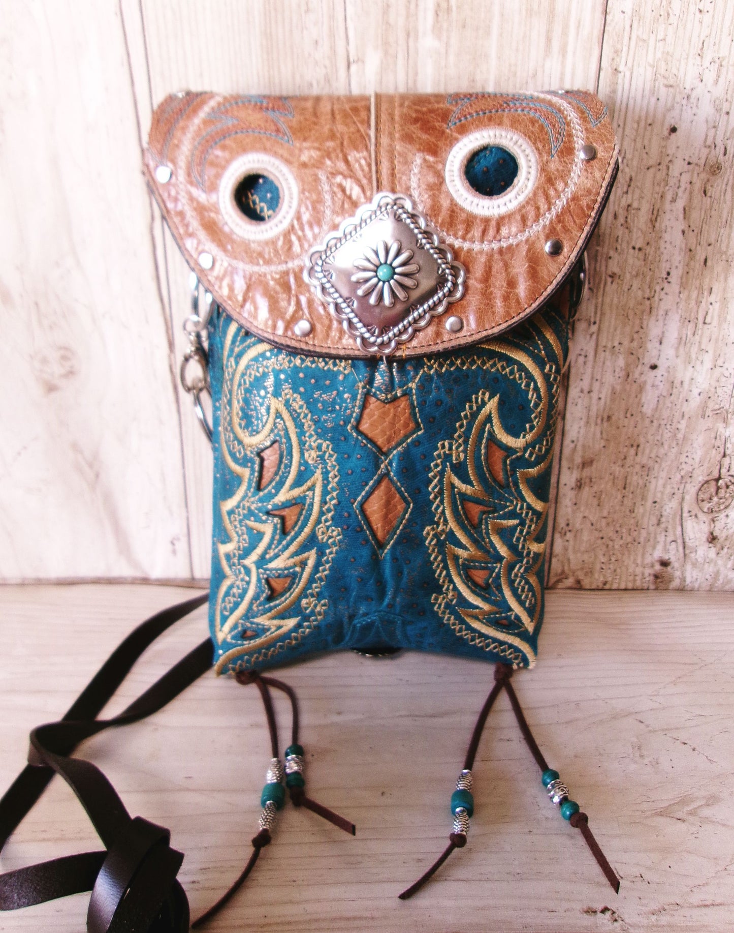 Decorative owl-shaped bag with leather and fabric design on a wooden surface