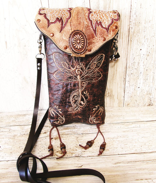 Decorative leather bag with intricate designs on a wooden surface