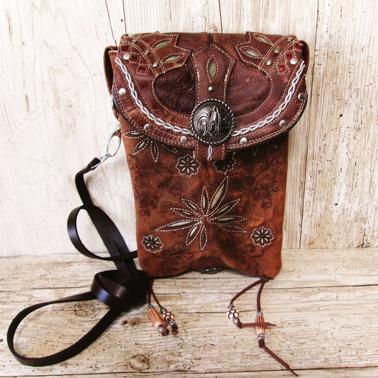 Brown leather handbag with intricate designs on a wooden surface