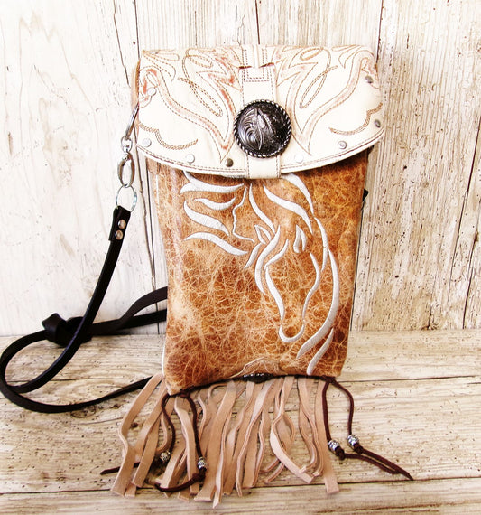 Leather handbag with fringe and embossed design on a wooden surface